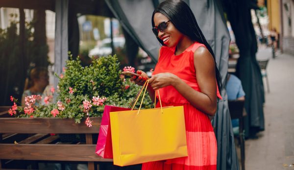 Black girl in a summer city. Woman with a shoping bags. Lady in a red ress