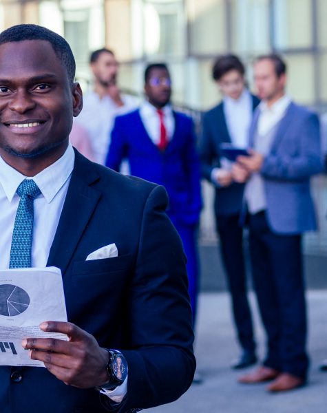 multinational and multiethnic corporate business people boss and colleagues partners standing and smiling on on the street background skyscraper windows