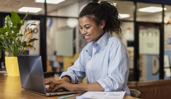 side-view-smiley-woman-working-with-laptop-office